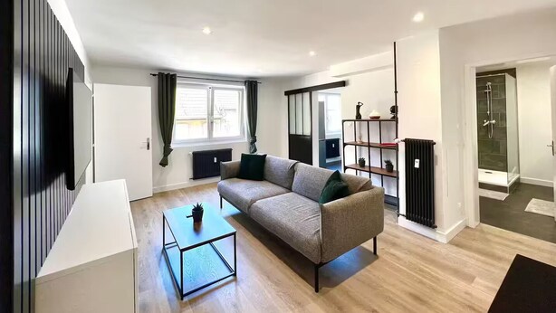 Uma sala de estar moderna com sofá, mesa de centro e box de vidro.
