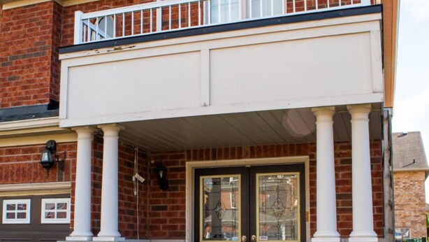 A two-story house with a balcony, a garage, and a stone foundation. - Cozy and Private Basement apartment / Ideal for Relaxation or Work (Brampton)
