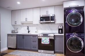 A modern kitchen with white cabinets, a microwave, an oven, and a washing machine. - Cozy and Private Basement apartment / Ideal for Relaxation or Work (Brampton)