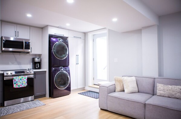 A modern kitchen with a microwave, oven, and washing machine. - Cozy and Private Basement apartment / Ideal for Relaxation or Work (Brampton)