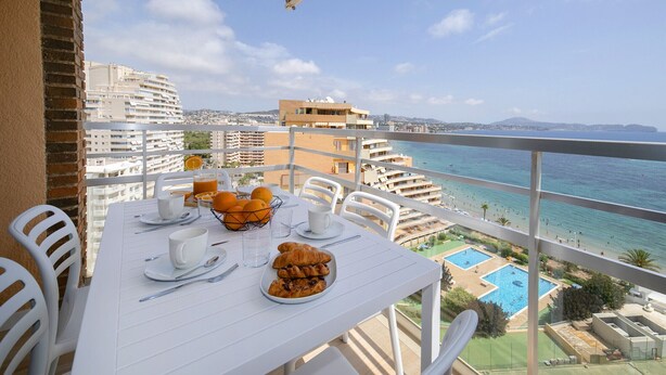Varanda com mesa posta para o café da manhã, com vista para a praia e área da piscina.