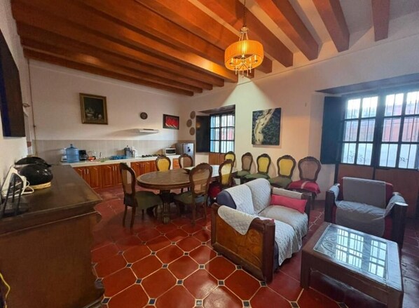 A cozy living room with a wooden ceiling, a dining table with chairs, a sofa, and a coffee table. - Casa Oaxaca! (Oaxaca de Juárez)