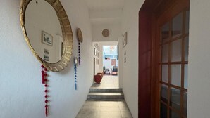Un couloir avec une porte en bois, un grand miroir et un escalier menant à une autre pièce.