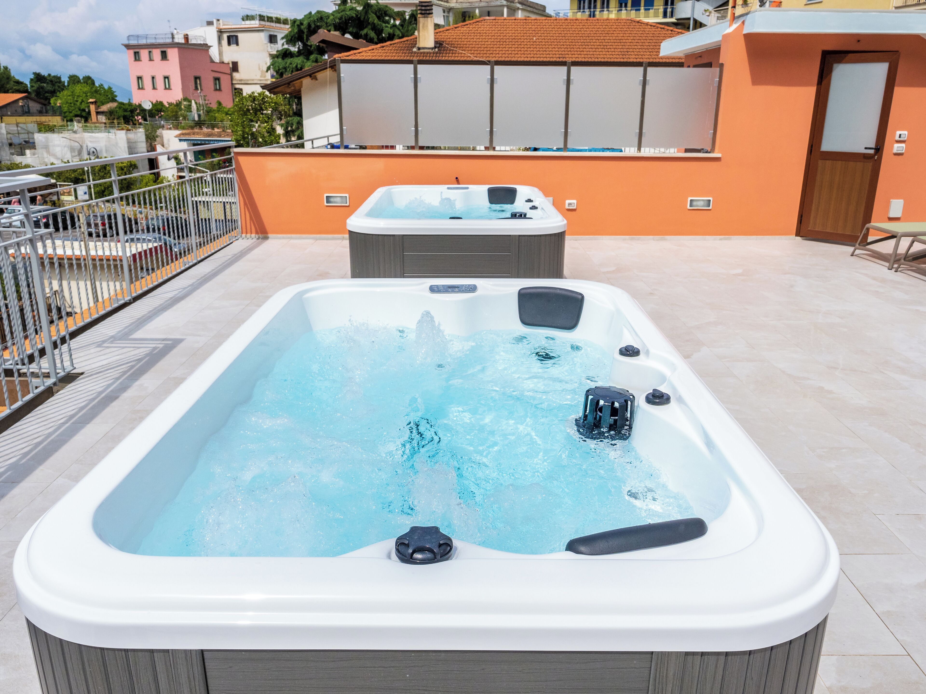 Een rechthoekig bubbelbad met jets, omringd door een betegeld terras.