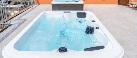 Een rechthoekig bubbelbad met jets, omringd door een betegeld terras.