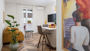 Un salon moderne avec un canapé, une table à manger et des chaises, une plante en pot et un tableau accroché au mur.