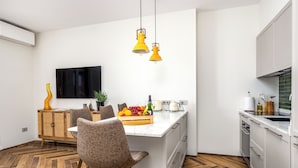 Une cuisine moderne dotée d’un îlot central, de meubles blancs et d’un coin repas avec des chaises à motifs.