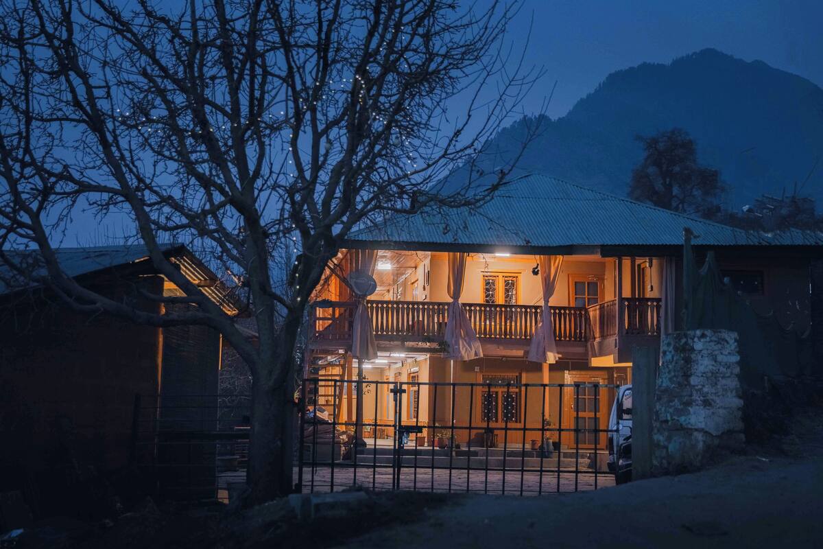 A two-story building with a balcony, a gated entrance, and a mountain in the background.