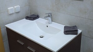 Une salle de bain avec un lavabo blanc, des meubles sombres et un miroir au-dessus du lavabo.
