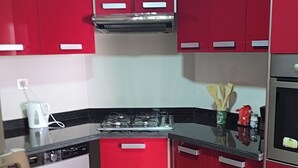 Une cuisine de taille réduite avec des placards rouges, un lave-linge et une cuisinière.