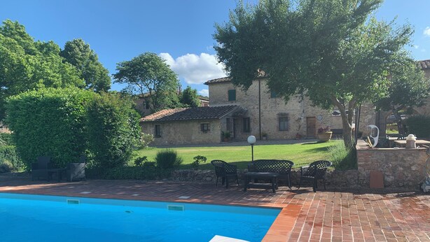 A swimming pool with a white deck, surrounded by a brick patio and a grassy lawn. - S.M.IL CASTRO a special place at the foot of the castle of Monteriggioni (Monteriggioni)