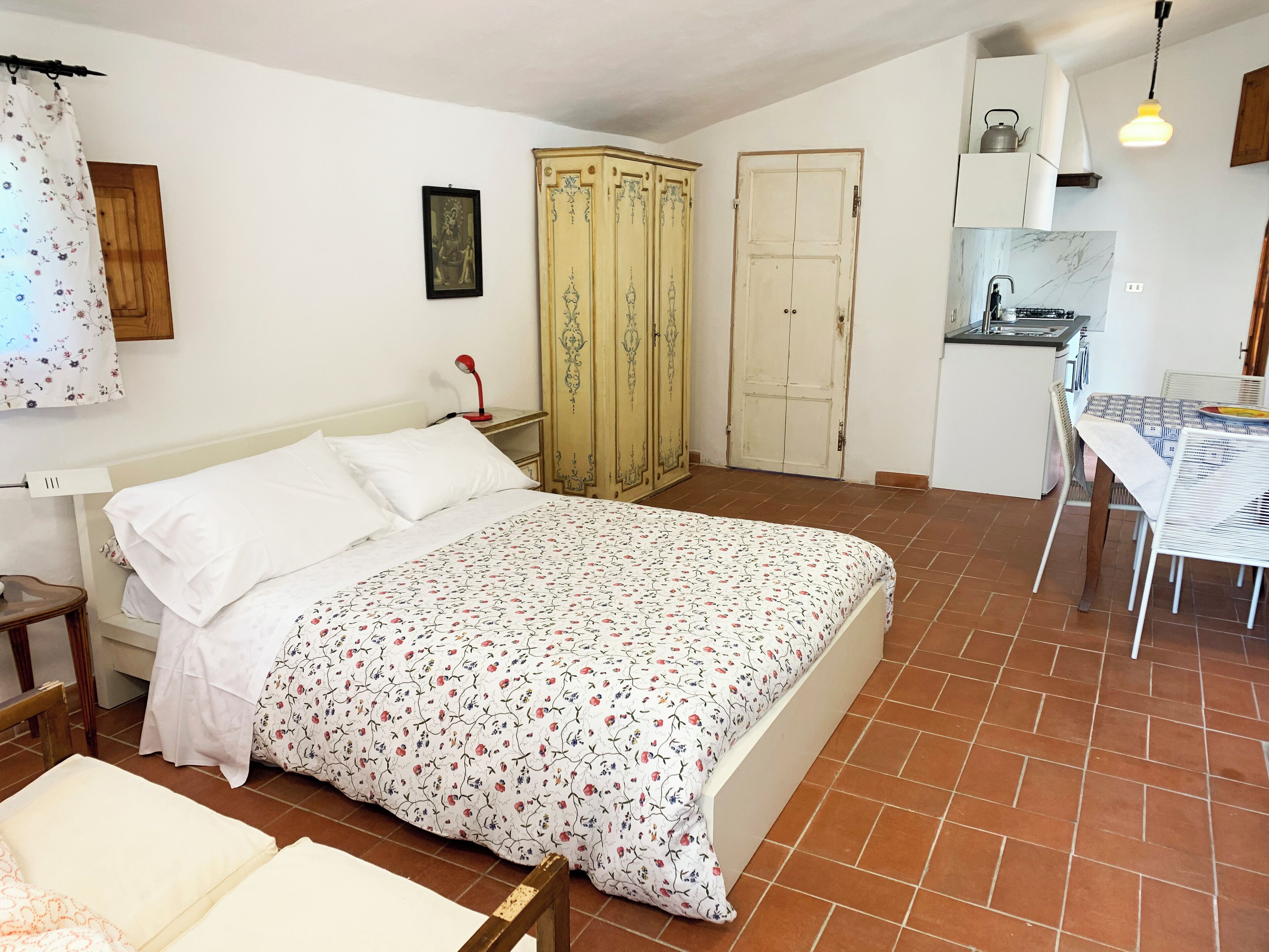 Ein Schlafzimmer mit einem Bett, einem Kleiderschrank, einem kleinen Tisch und einer Küchenzeile.