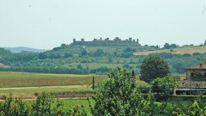 A castle on a hill with surrounding greenery and fields. - S.M.IL CASTRO a special place at the foot of the castle of Monteriggioni (Monteriggioni)