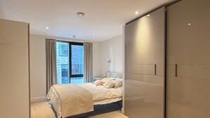 Une chambre moderne avec un grand lit, une armoire à portes coulissantes et une fenêtre avec des rideaux.