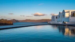 A coastal resort with a clear pool, white buildings, and a mountainous backdrop. - The Duchess (Therasia)