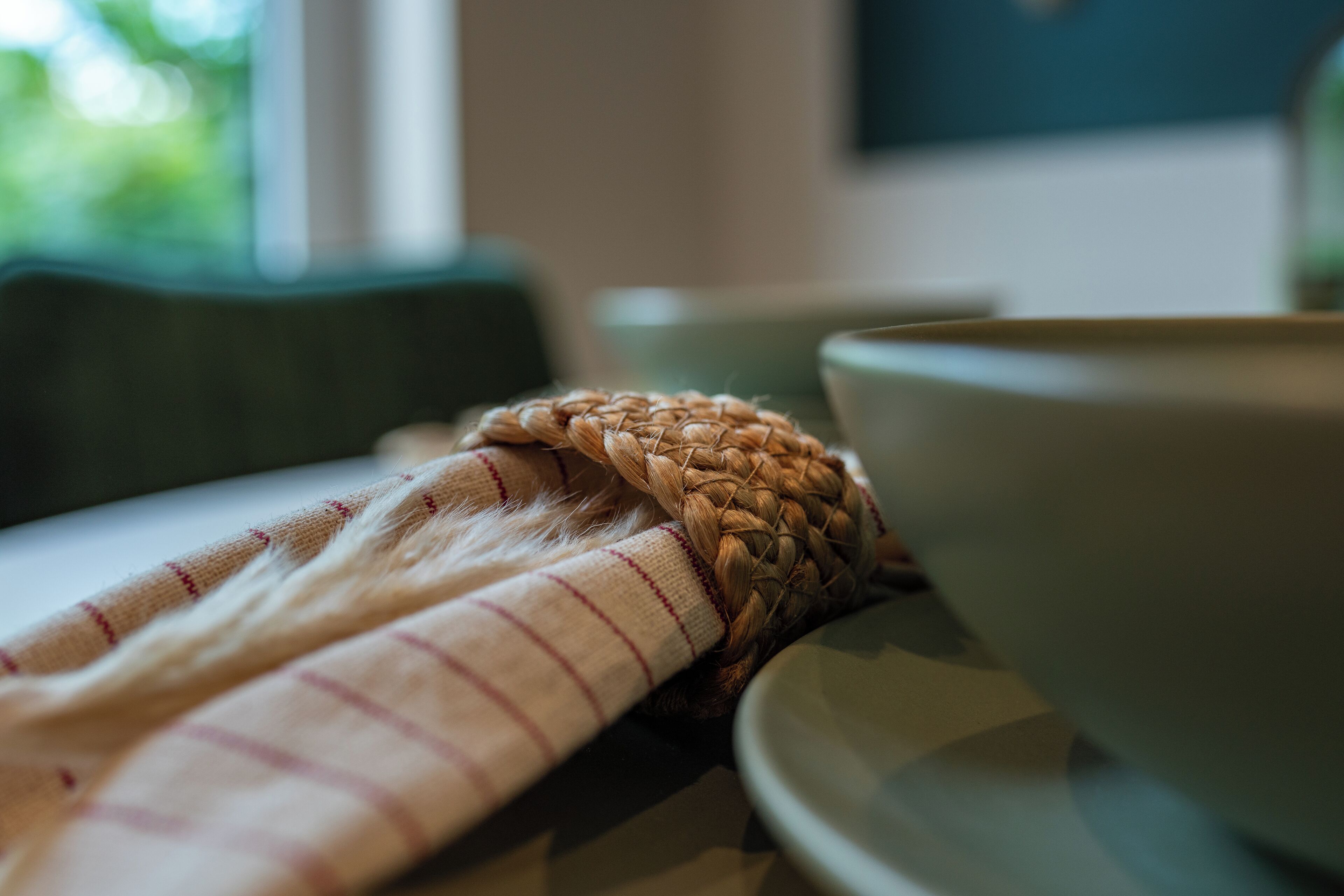 A woven basket and a striped cloth on a table with a bowl.