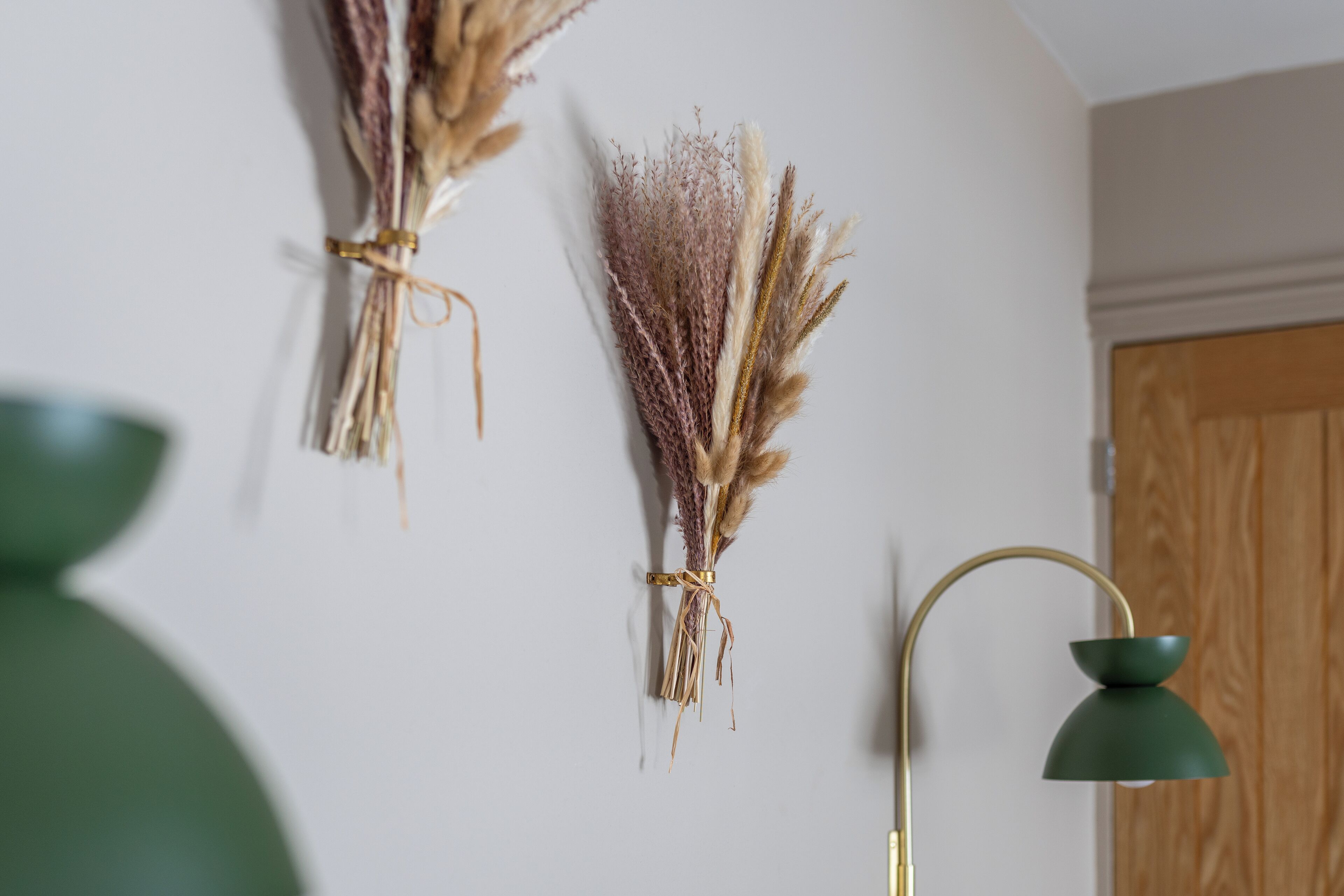 A room with a wall-mounted lamp and dried plants.