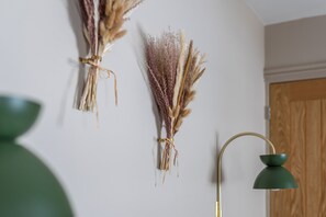Ein Zimmer mit einer Wandlampe und getrockneten Pflanzen.