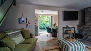 Un salon moderne avec un canapé vert, un pouf à rayures et une cheminée en pierre.