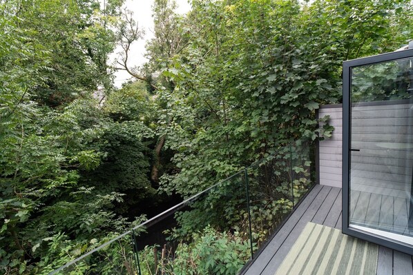 Eine moderne Außenterrasse mit Glasveranda, umgeben von dichtem Grün.