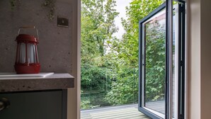 Une pièce dotée d’une porte-fenêtre coulissante donnant sur un balcon avec vue sur la verdure.