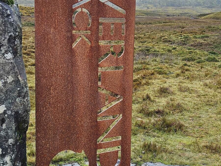 A sign for the Overland Track with a logo and a map of Tasmania.