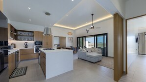 Uma cozinha moderna com uma ilha central, um espaço de refeições com sofá e uma grande janela com vista para o exterior.