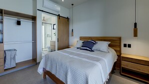 Quarto moderno com cama de madeira, roupeiro embutido e closet com porta deslizante.
