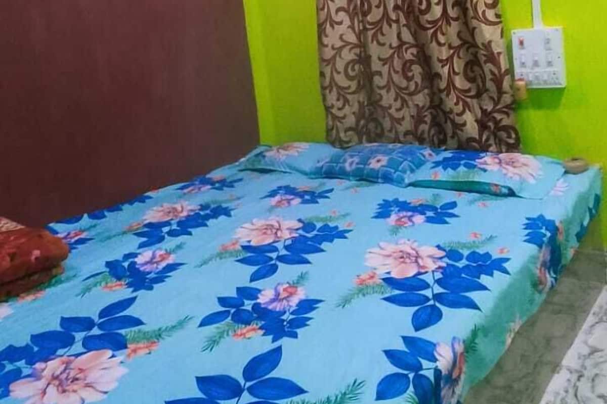A room with a bed, a ceiling fan, a green wall, and a window with curtains.