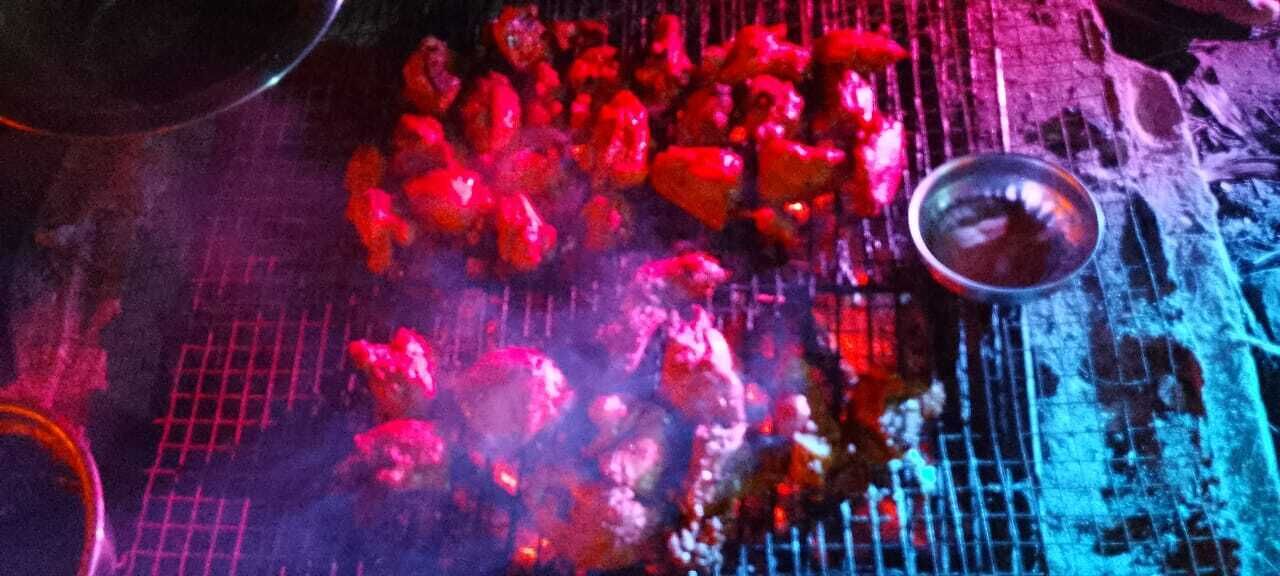 A grill with food being cooked, a metal bowl, and a grid-like structure.