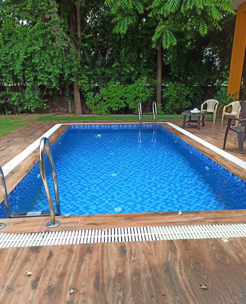 A rectangular swimming pool with a wooden deck surrounding it.