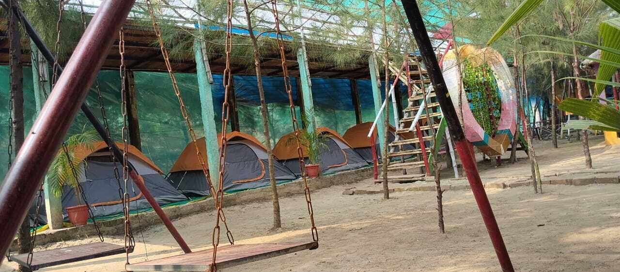 A playground with swings and a covered area with tents.