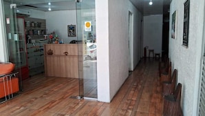 Un pasillo con mostrador de recepción, separador de vidrio y banca de madera.