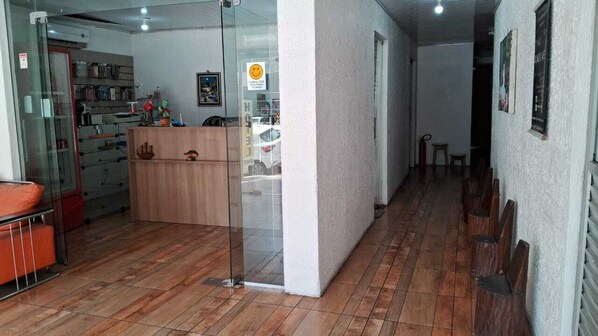 A hallway with a reception desk, a glass partition, and a wooden bench.