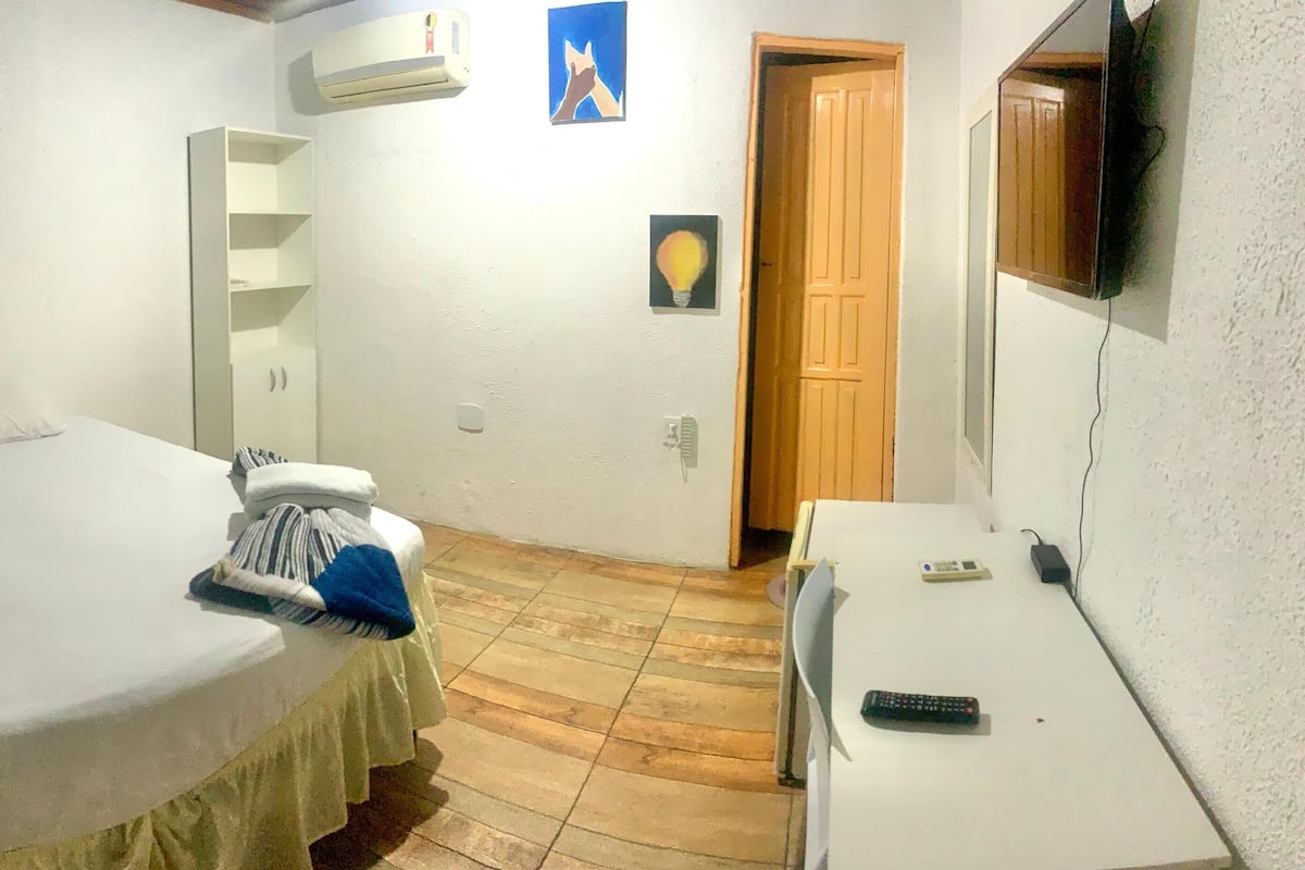 A bedroom with a bed, a wardrobe, a desk, and a TV.