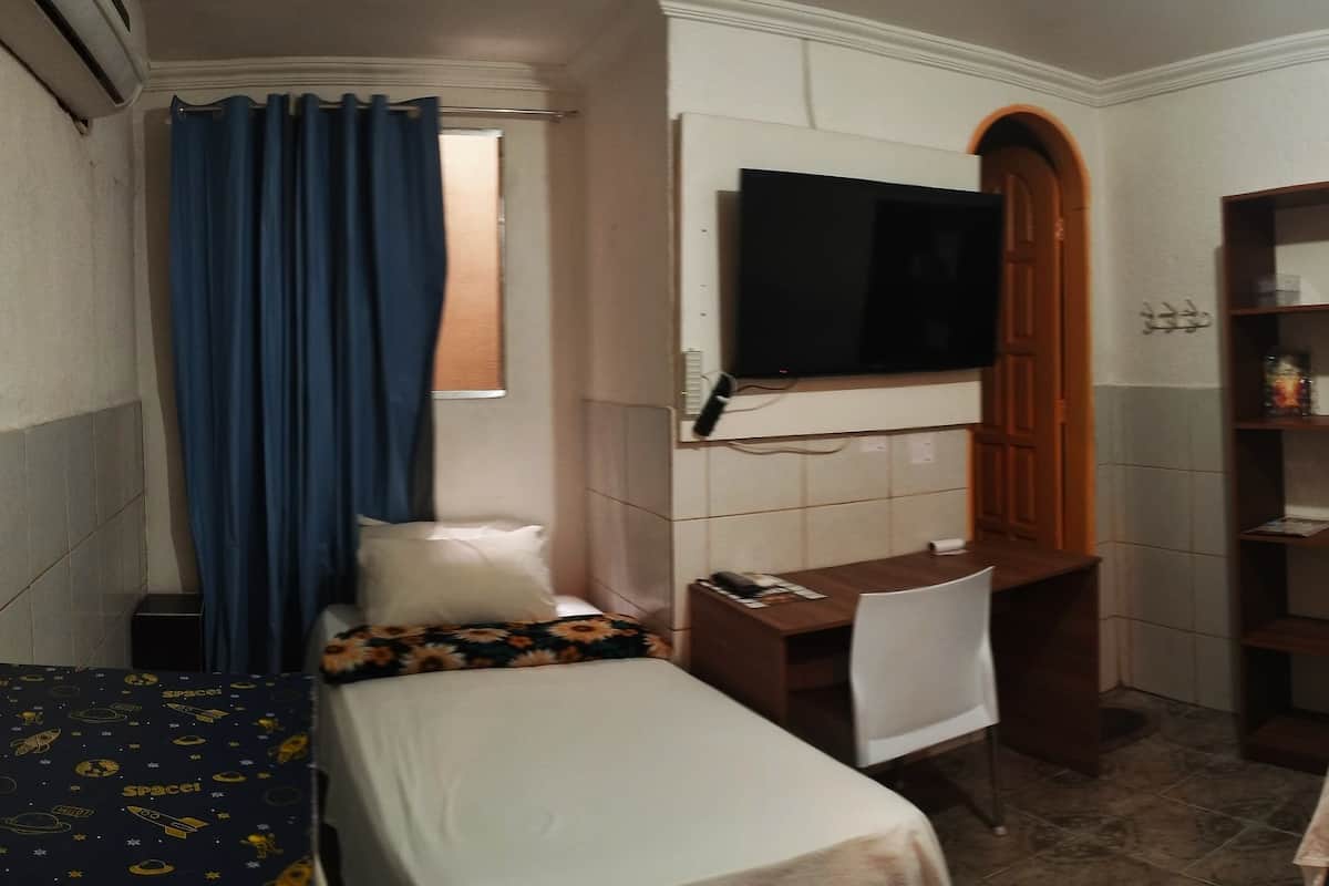 A hotel room with two beds, a desk, a TV, and a bathroom.
