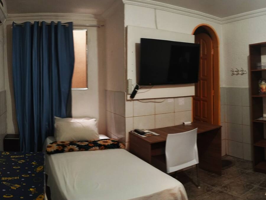 A hotel room with two beds, a desk, a TV, and a bathroom.