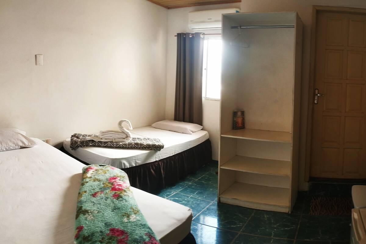 A bedroom with a bed, a small table, a wardrobe, and a TV mounted on the wall.
