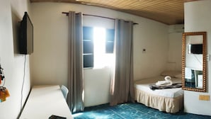 Una habitación de hotel pequeña con una cama, un escritorio, un televisor montado en la pared, un espejo y una puerta.