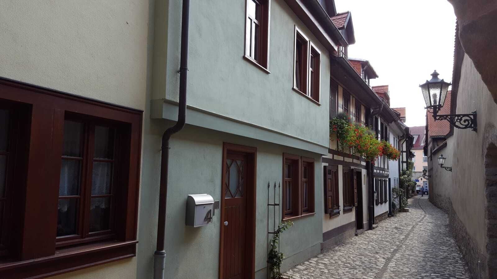 Eine enge Kopfsteinpflasterstraße gesäumt von traditionellen europäischen Gebäuden, mit Holzläden und einem Briefkasten.