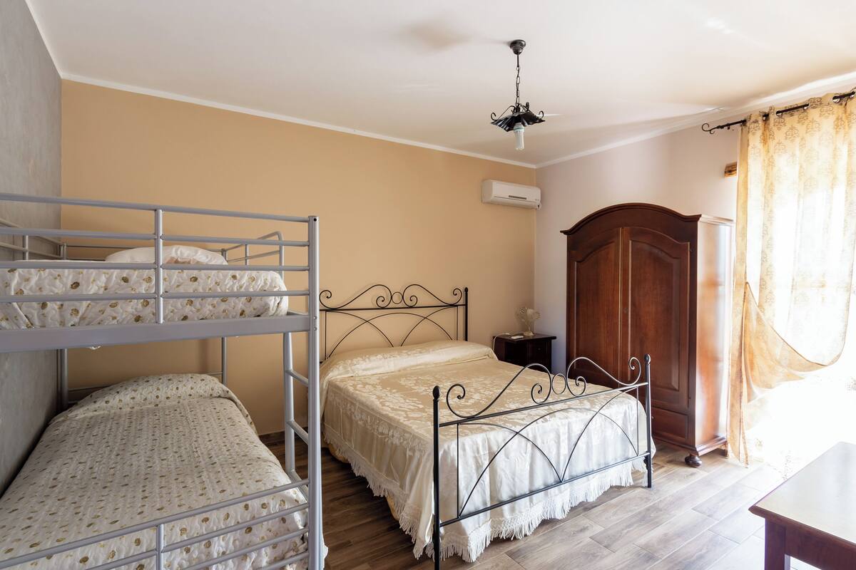 A bedroom with bunk beds, a wooden wardrobe, and a ceiling light fixture.
