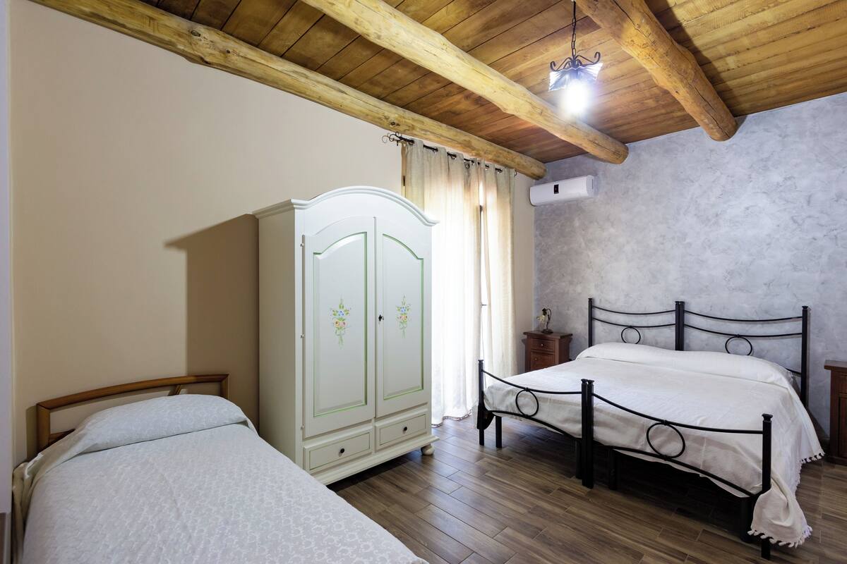 A bedroom with two beds, a wardrobe, and a ceiling with exposed beams.