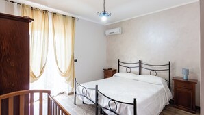 A bedroom with a bed, wooden headboard, bedside tables, and a ceiling light fixture.