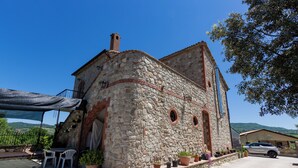 A stone building with a balcony, outdoor seating, and potted plants.