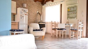 A cozy room with a bed, a desk, and a chair. There is a refrigerator and a lamp. - Villetta Rosmarino 1700 meters from the wonderful beaches of Chia (Sardegna)