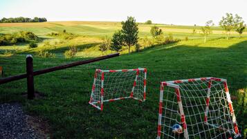 Two soccer goals in a grassy field with a fence in the foreground.