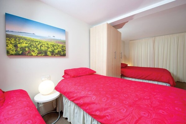 A hotel room with two beds, a bedside table with a lamp, and a large landscape painting on the wall. - Amazing Stables Building,with 12 bedrooms, Lyndhurst, centre of New Forest! (Lyndhurst)