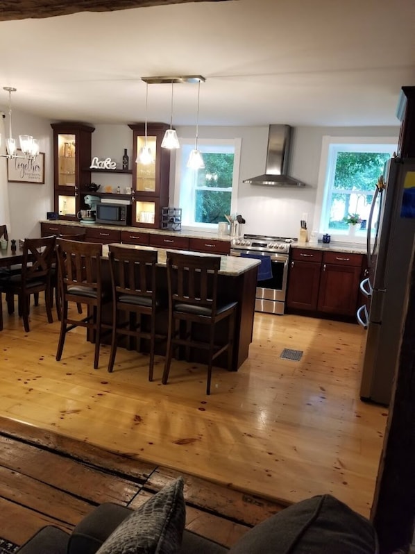 A modern kitchen with a central island, wooden chairs, and a dining table. - LAKEFRONT COMFORT (Chazy)