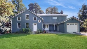 A two-story house with a garage, a front porch, and a well-maintained lawn. - LAKEFRONT COMFORT (Chazy)