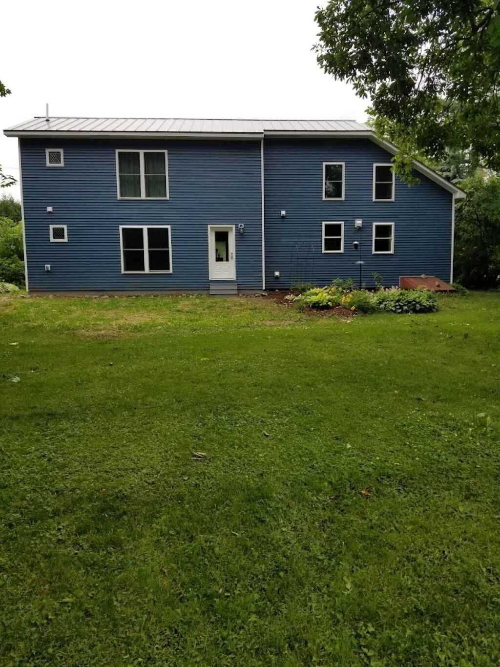 A two-story blue house with a front door, windows, and a small porch area.